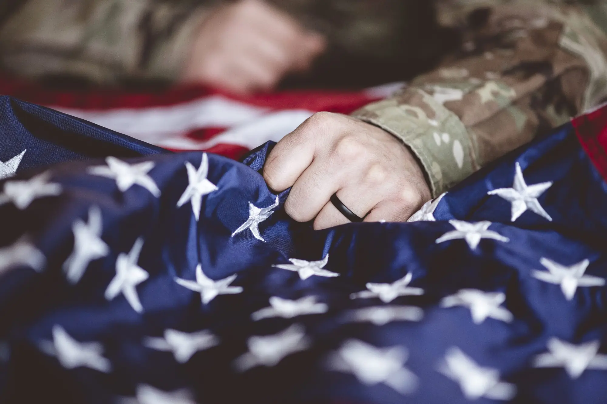 Service member's hand resting on an American flag